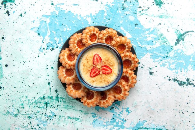 Foto gratuita vista dall'alto deliziosi biscotti con marmellata e dessert alla fragola sulla torta biscotto dolce zucchero di superficie azzurra