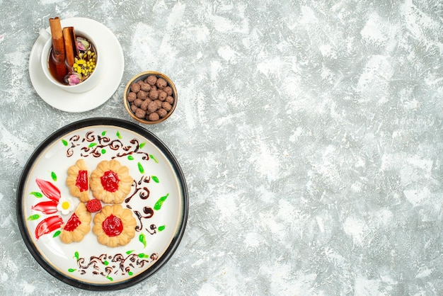 Top view delicious cookies with red jelly inside plate on white background sugar biscuit cake cookies sweet tea