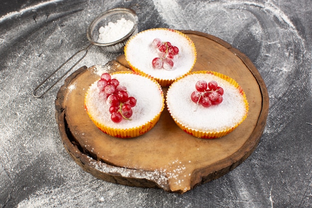 Top view delicious cranberry cakes with red cranberries on top sugar pieces and powder grey background cake biscuit sweet bake