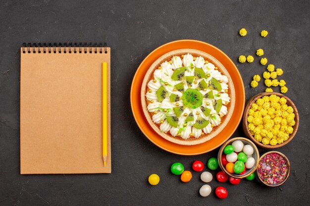 Top view delicious cream dessert with candies on a dark background color candy biscuit cream dessert