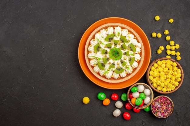 Top view delicious cream dessert with candies on dark background color candy biscuit cream dessert