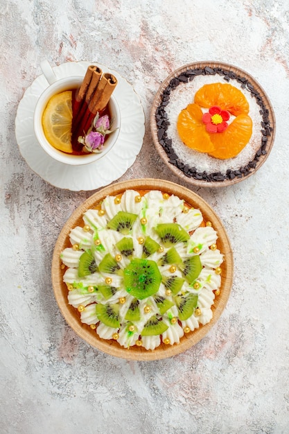 Top view delicious cream dessert with cup of tea on the white desk color candy biscuit cream dessert