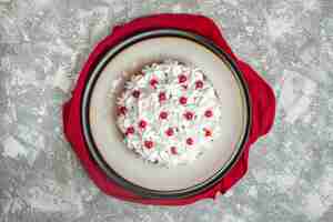 Foto gratuita vista dall'alto di una deliziosa torta cremosa decorata con frutta su un asciugamano rosso su sfondo di ghiaccio