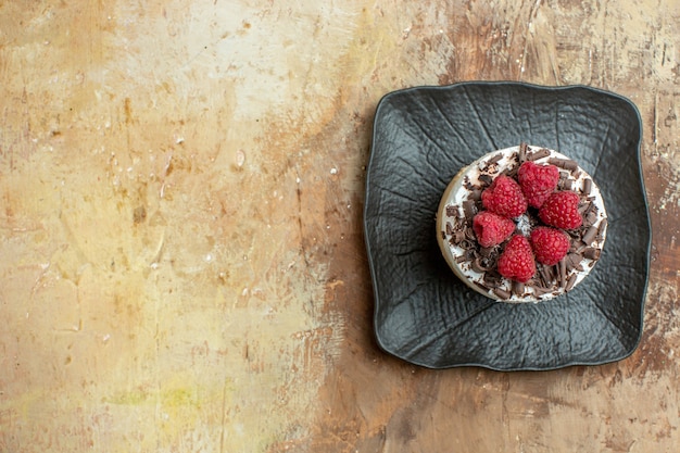 Top view delicious creamy cake inside plate with fresh raspberries on brown background