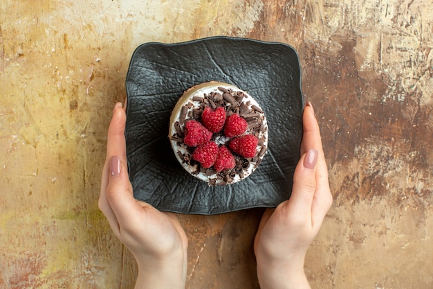 Top view delicious creamy cake inside plate with fresh raspberries on brown background