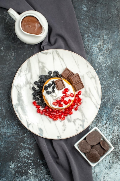 Top view delicious creamy cake with chocolate and raisins on a light-dark background