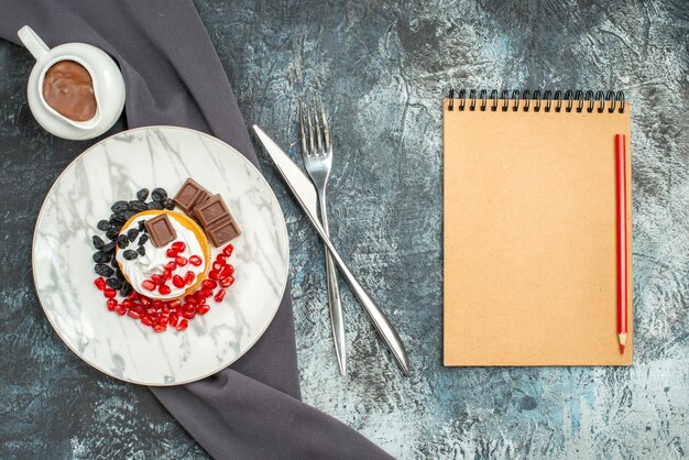 Top view delicious creamy cake with chocolate and raisins on light-dark background