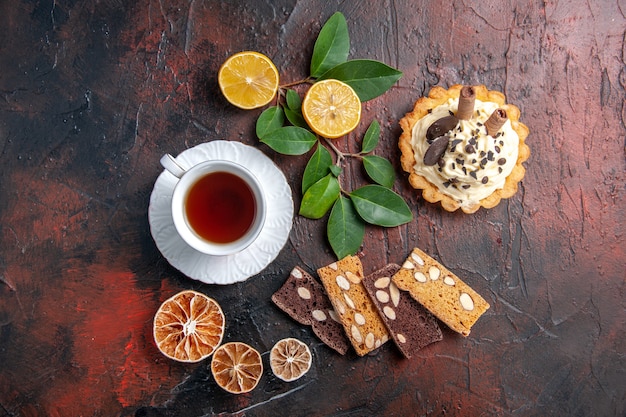 Vista dall'alto deliziosa torta cremosa con una tazza di tè sul dessert torta dolce tavolo scuro