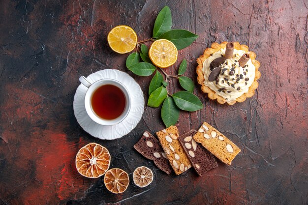 Top view delicious creamy cake with cup of tea on dark table sweet cake dessert