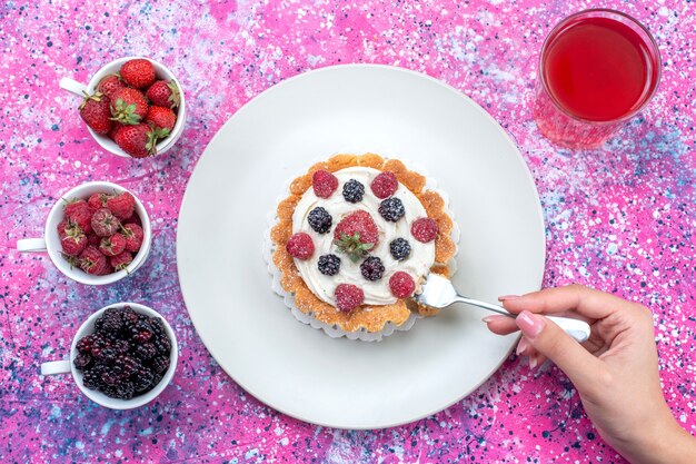 top view of delicious creamy cake with different fresh berries juice on bright-light, berry fruit fresh sour