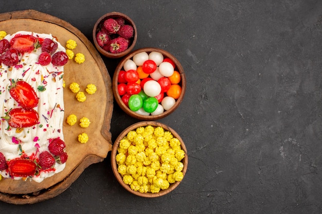 Top view delicious creamy cake with fruits and candies on dark background biscuit tea cookie cake sweet cream candy