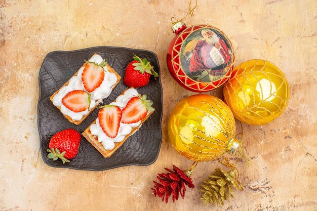 Top view delicious creamy cakes with new year tree toys on light background