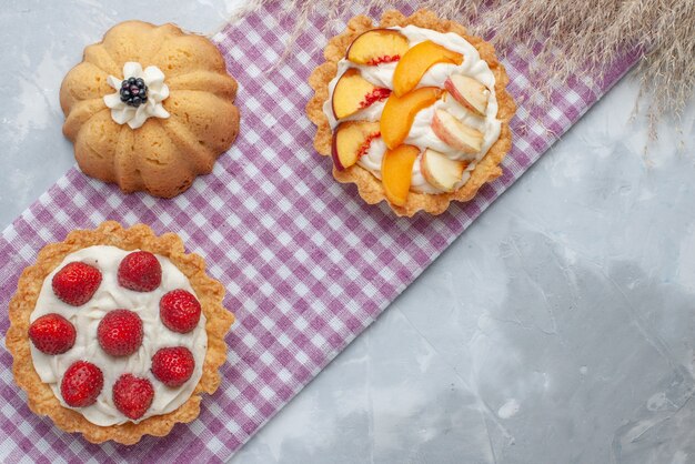 ライトデスクにスライスしたフルーツとおいしいクリーミーなケーキの上面図、ケーキビスケット甘いクリーム焼き茶砂糖