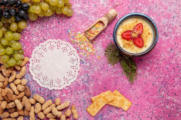 Top view delicious creamy dessert with fresh grapes crackers and peanuts on light-pink background dessert ice-cream berry cream sweet fruit