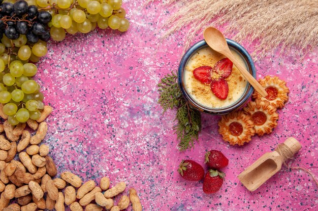 Top view delicious creamy dessert with fresh green grapes cookies and peanuts on light pink background dessert ice-cream berry cream sweet fruit