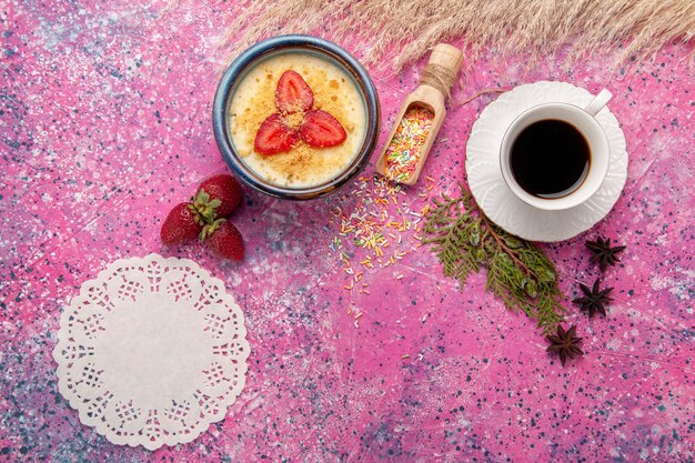 Top view delicious creamy dessert with red sliced strawberries and cup of tea on the light-pink background dessert ice-cream berry cream sweet fruit