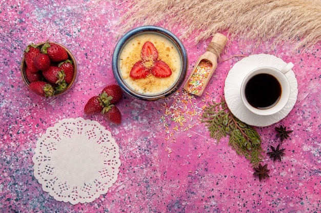 Top view delicious creamy dessert with red sliced strawberries and cup of tea on light-pink desk dessert ice-cream berry cream sweet fruit