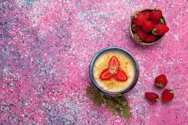 Top view delicious creamy dessert with red sliced strawberries and fresh ones on light pink background dessert ice-cream cream color sweet ice