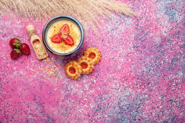 밝은 분홍색 배경에 빨간 슬라이스 딸기와 작은 쿠키가있는 상위 뷰 맛있는 크림 디저트 디저트 아이스크림 베리 크림 달콤한 과일