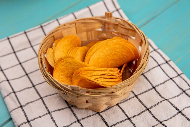 Top view of delicious crispy chips on a bucket on a checked cloth