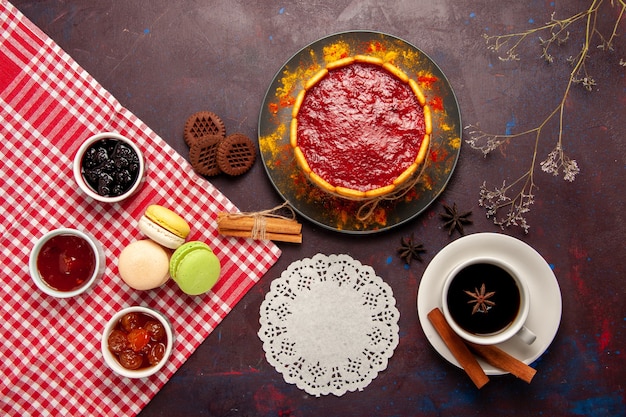 Top view delicious dessert cake with cup of coffee and fruit jams on dark surface biscuit sugar cookies cake dessert sweet