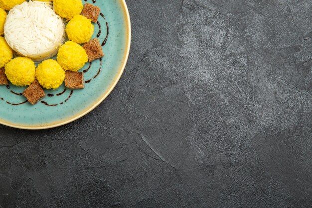 Top view delicious dessert little yellow candies with cake inside plate on grey background candy tea sugar cake sweet cookie