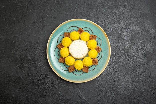 Top view delicious dessert little yellow candies with cake inside plate on a grey background candy tea sugar cake sweet
