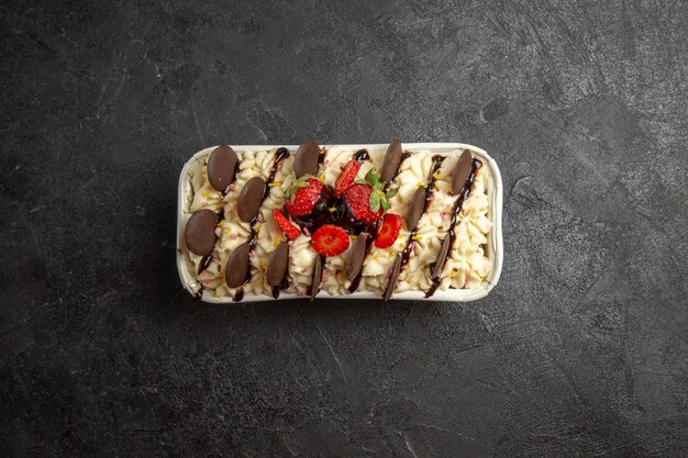 Вид сверху вкусный десерт с шоколадным печеньем и свежей клубникой на темном фоне ореховое сладкое фруктовое ягодное бисквитное печенье