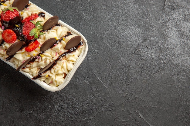 Vista dall'alto delizioso dessert con biscotti al cioccolato e fragole fresche su biscotto scuro con frutta secca e frutti di bosco