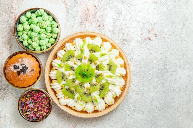 Top view delicious dessert with sliced kiwis and candies on white background cake biscuit dessert cream fruit candy