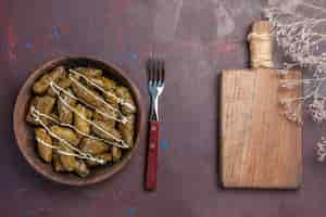 Foto gratuita vista dall'alto delizioso piatto di carne orientale dolma con foglie e carne macinata su tavola scura cibo calorico cena olio piatto carne