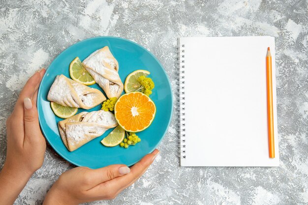 Top view delicious dough pastries with lemon slices on white desk pastry sugar bake cake dough sweet pie