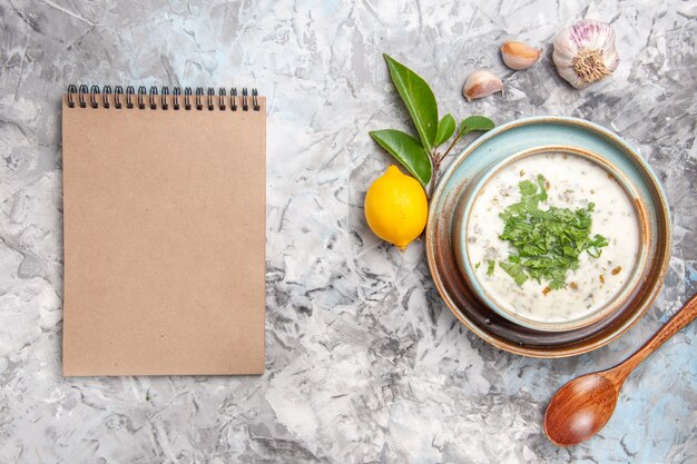 Top view delicious dovga yogurt soup with greens on white floor milk soup dish dairy