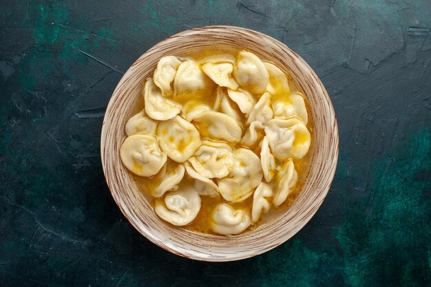 Top view delicious dumpling soup on dark-green surface food dough meat vegetable soup