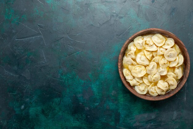 濃い緑色の背景の茶色のプレート内のおいしい餃子スープの上面図食品生地野菜スープ肉