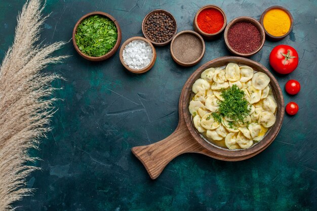 Top view delicious dumpling soup with different seasonings on the green surface food meat vegetable dough soup
