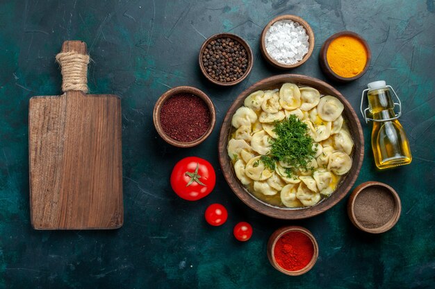 Top view delicious dumpling soup with different seasonings on green surface meat vegetable dough soup food