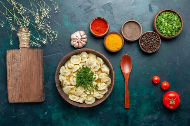 Top view delicious dumpling soup with greens and different seasonings on the dark surface soup dough vegetable food