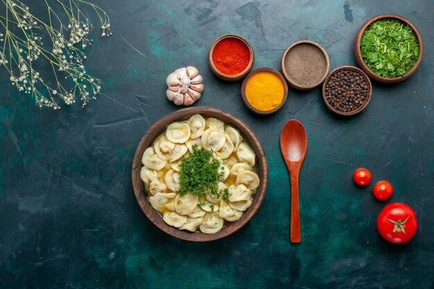 Top view delicious dumpling soup with greens and different seasonings on dark surface soup dough vegetables food