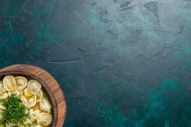 Top view delicious dumpling soup with greens on the green background meat vegetable dough food soup