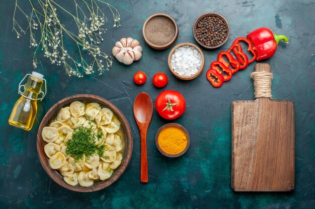 Top view delicious dumpling soup with oil seasonings and tomatoes on green surface food meal soup meat