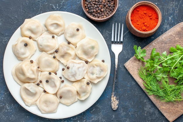 Top view of delicious dumplings inside plate along with pepper and greens on dark, dough meal food dinner meat calorie