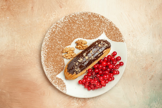 Top view delicious eclair with red berries on light table cake dessert sweet