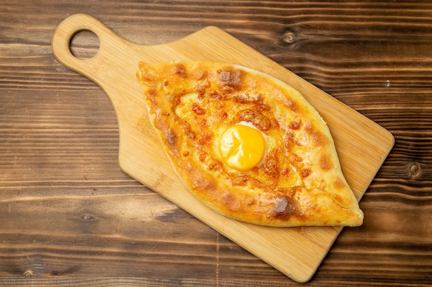 Foto gratuita vista dall'alto delizioso pane all'uovo cotto sul tavolo in legno marrone pane panino cuocere l'uovo della colazione