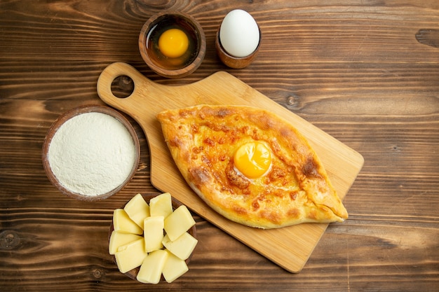 Вид сверху вкусный яичный хлеб, испеченный на коричневом деревянном столе, булочка с завтраком, тесто для яиц