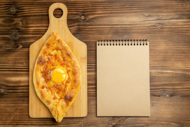 Vista dall'alto delizioso pane all'uovo cotto sul panino di pane tavolo in legno marrone cuocere le uova della colazione