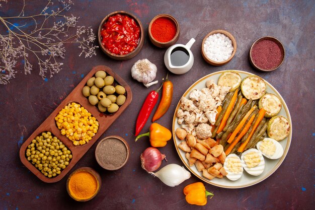 Top view delicious egg meal with cooked vegetables and seasonings on dark space