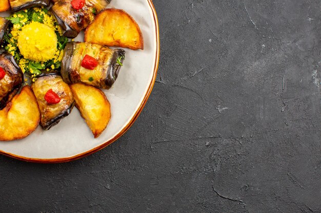 Вид сверху вкусные рулетики из баклажанов, приготовленное блюдо с печеным картофелем на темном фоне, блюдо для еды, приготовление еды, запекание картофеля