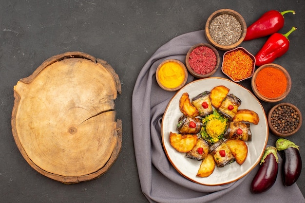 Вид сверху вкусные рулетики из баклажанов, приготовленное блюдо с печеным картофелем и приправами на темном фоне блюдо для приготовления картофеля