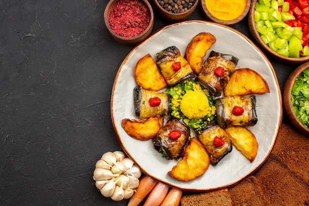 Top view delicious eggplant rolls cooked dish with potatoes and bread loafs on the dark background cooking food fry dish bake potato